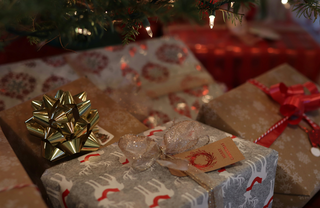 Close-up of beautifully wrapped Christmas presents under a tree with bows, ribbons, and festive paper