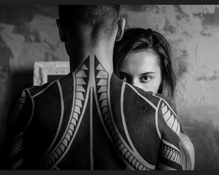 Silhouette of a nude man in front with a woman starting right into camera over his shoulder